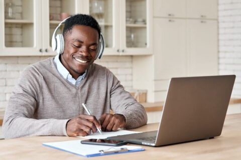 young man with headphones in front of laptop in kitchen